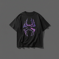A dark gray oversized t-shirt hanging on a wooden hanger, featuring a large purple and pink spider graphic on the front.